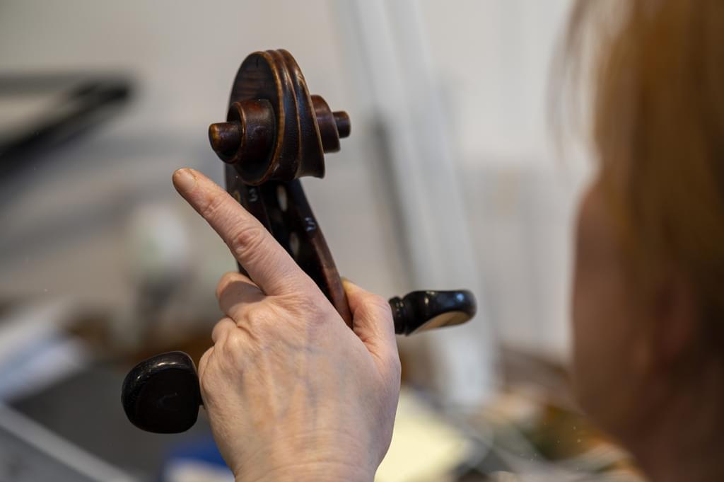 A hands holds the back of a violin neck