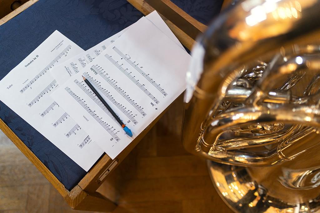 A manuscript and pencil next to a trumpet
