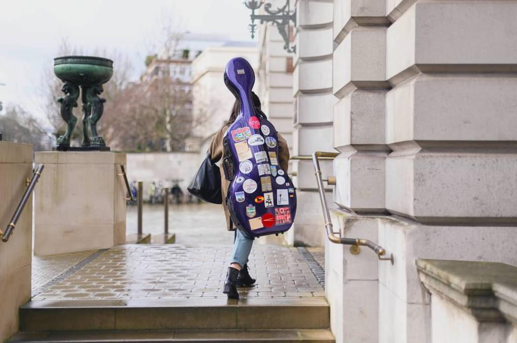 A Student enters the Academy's front entrance carrying a Cello