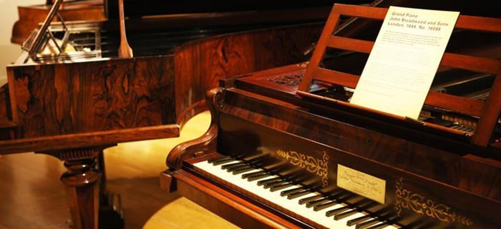 Two pianos from the Broadwood collection alongside one another, with keyboard and manuscript on one piano in the foreground and the body of the second in the background.