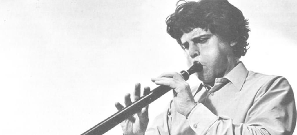Scanned black and white image of a musician blowing into a bass recorder