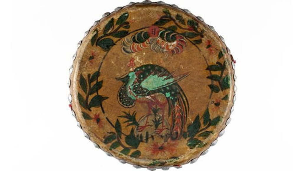 A tambourine with a multicoloured peacock illustration painted on the skin