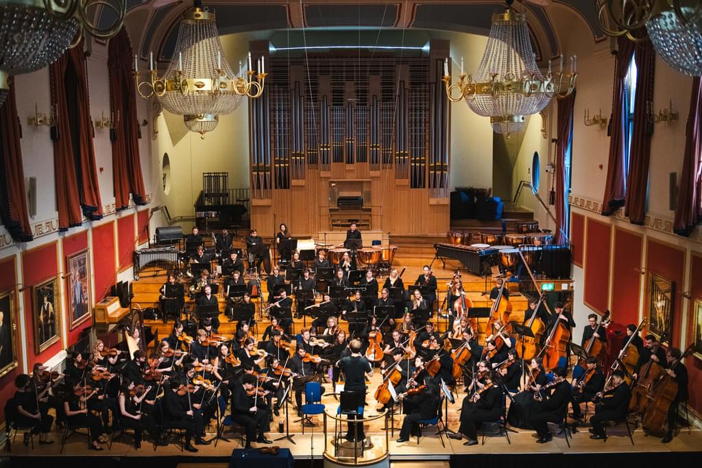 An image of the Academy Symphony Orchestra in rehearsal on the stage of the Duke's Hall