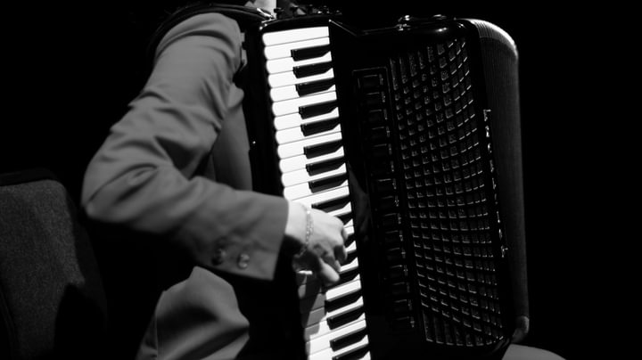 A close-up, black and white image of a hand playing the keys of an accordion