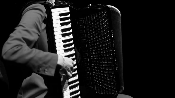 A close-up, black and white image of a hand playing the keys of an accordion