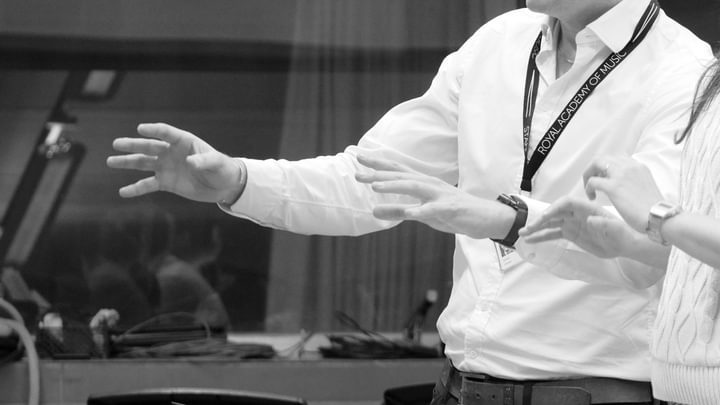 A close-up, black and white image of two conductors' hands in action