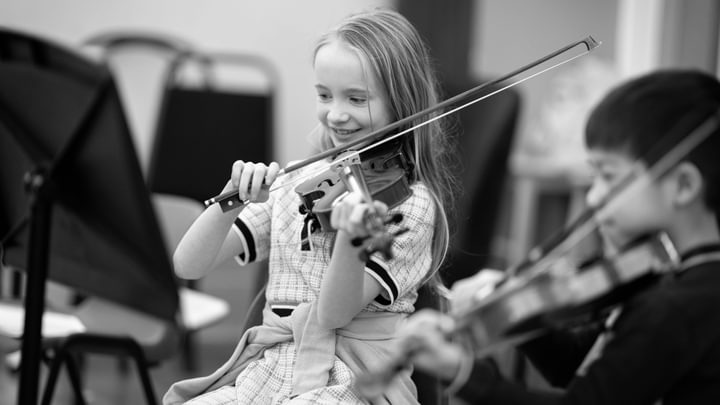 A young violinist smiling while playing the violin