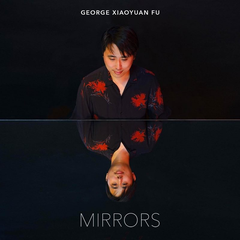 Front cover for George Xiaoyuan Fu's debut album, Mirrors. George sits looking at his own reflection on the top cover of a black piano