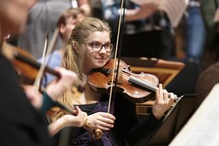 A string student in rehearsal, smiling
