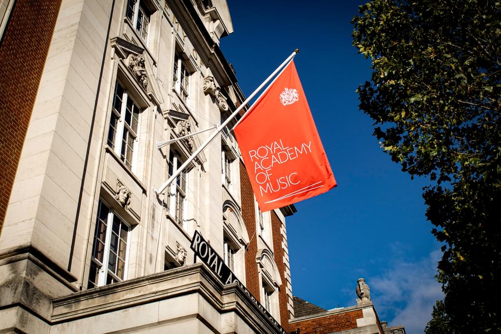The Academy flag hoisted at the front of the main building against a clear sky on a sunny day