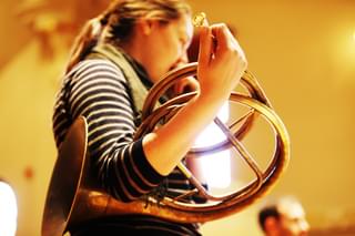 Side view of a Historical Horn student performing