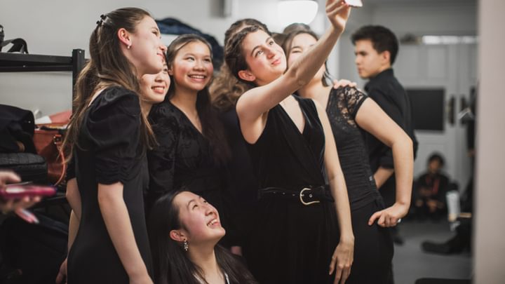 A group of young musicians smile and take a selfie