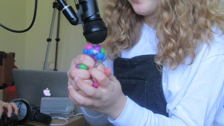 A young participant squeezes a sensory toy near a microphone