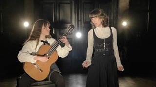 A guitarist and singer face each other during an expressive performance