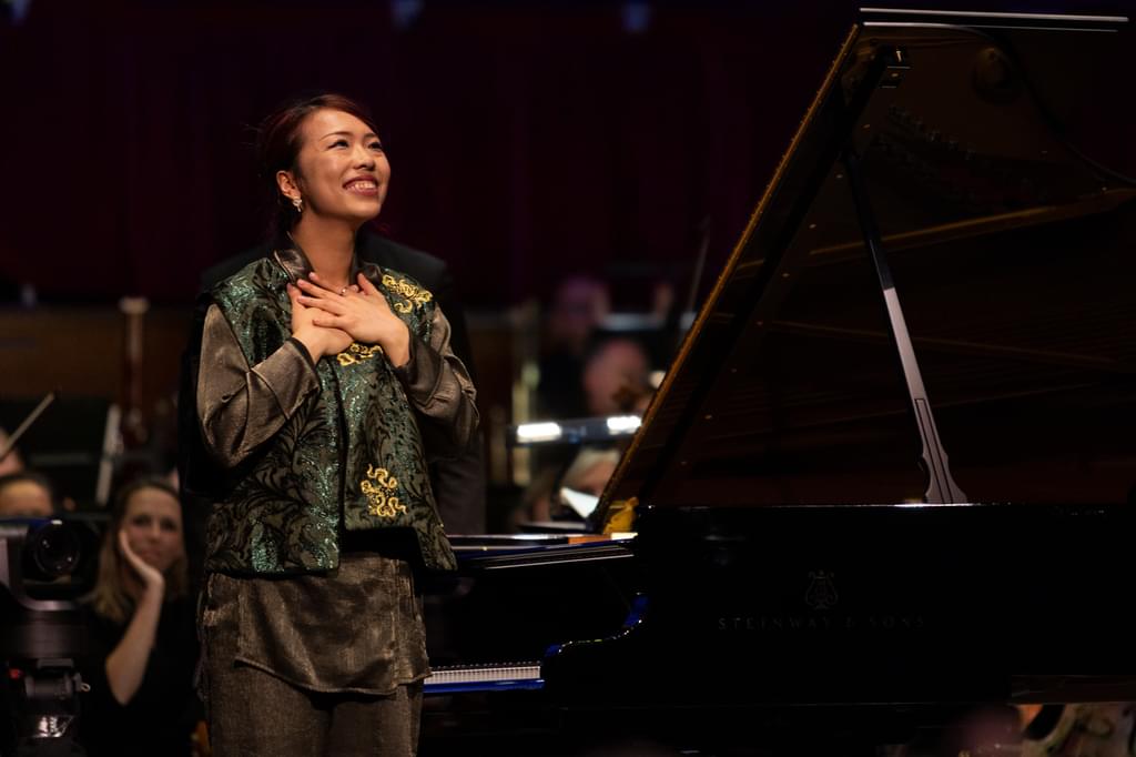 Junyan Chen standing on stage, smiling, after the Final of the Leeds International Piano Competition