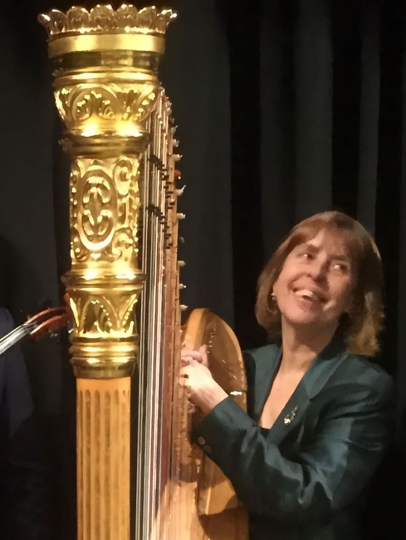 Miriam Keogh stands at a harp, smiling