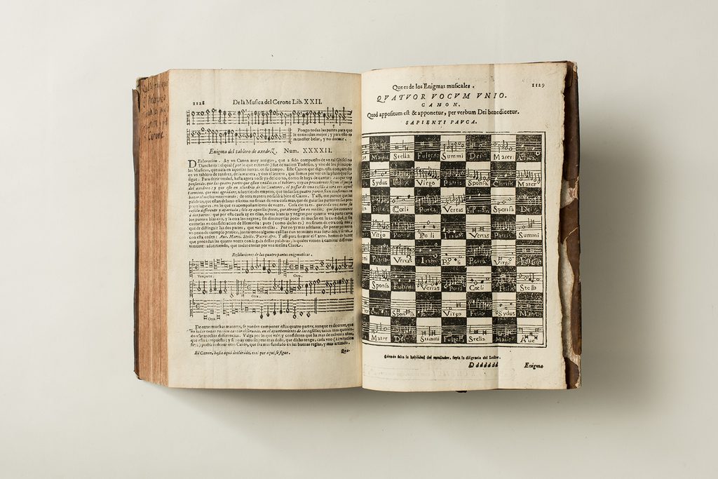 An ancient book lies open, showing text and musical symbols.