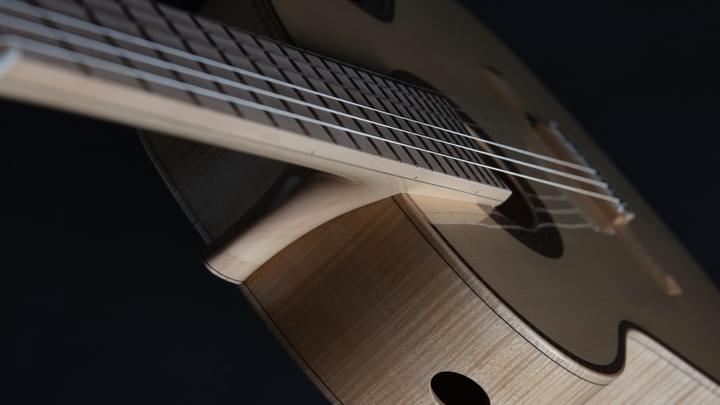 A top down view of a light wood acoustic guitar on a dark background