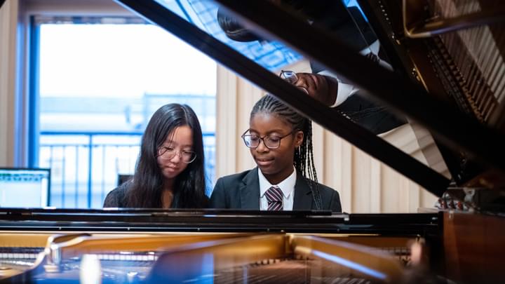 Two young people at a piano keyboard