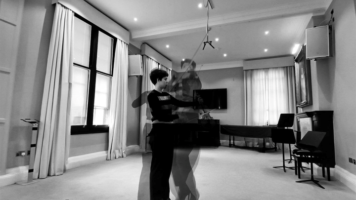 A blurred violinist performs in a practice room at the Academy