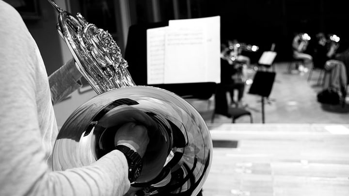 View over the shoulder of a horn player, looking out onto a music stand and empty auditorium (black and white)
