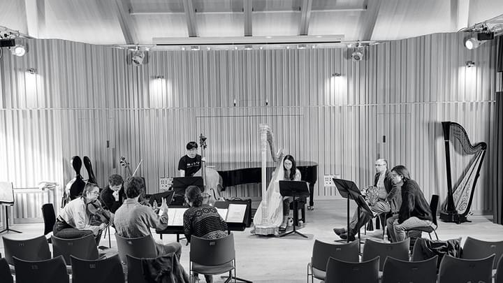 Students in a recital hall, reading manuscript and discussing (black and white)