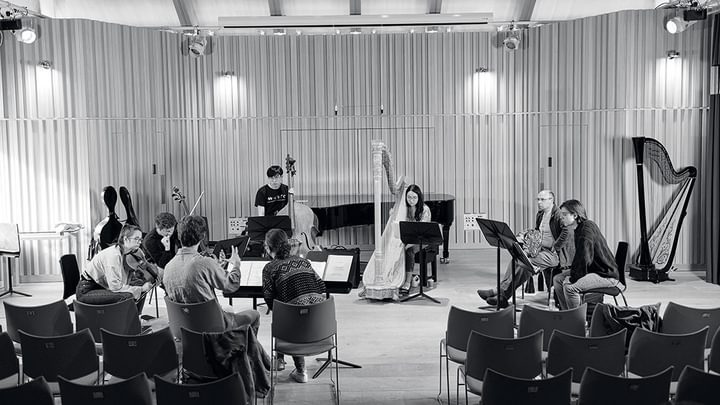 Students in a recital hall, reading manuscript and discussing (black and white)