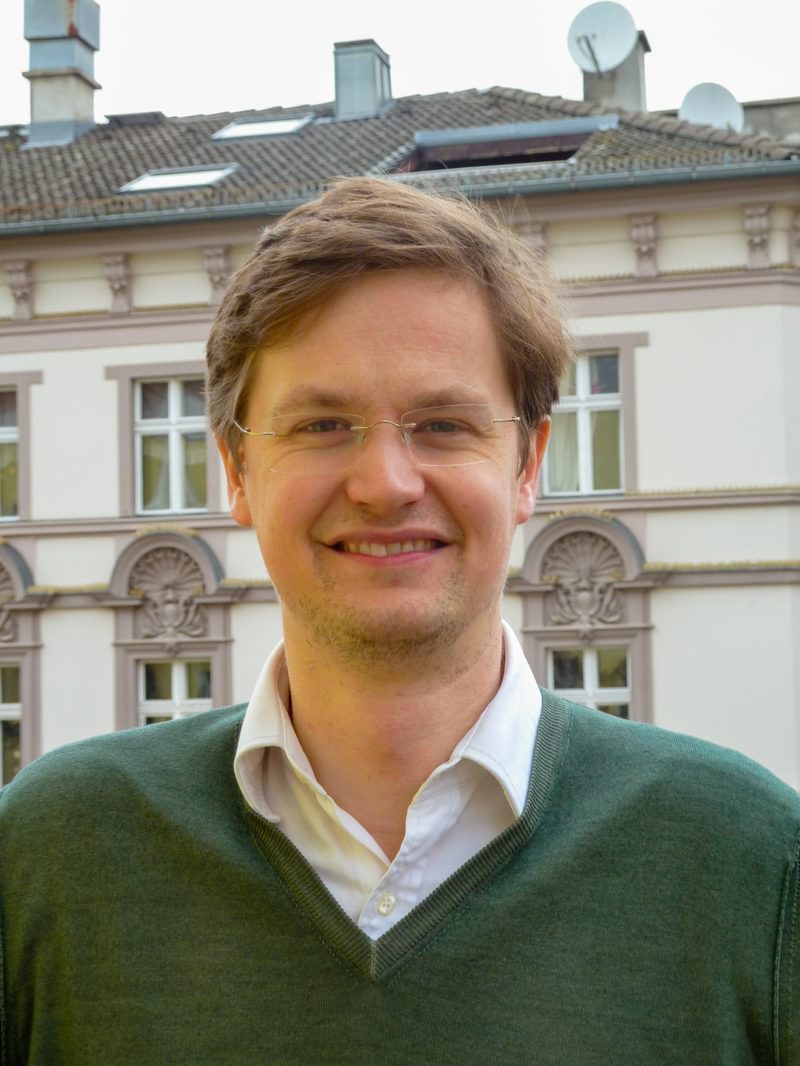 Dr Christopher White poses for a headshot, smiling to camera