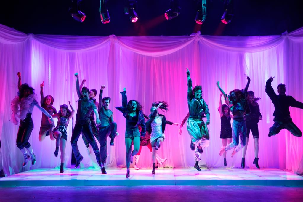 Dancers perform a musical theatre number on a colourful stage