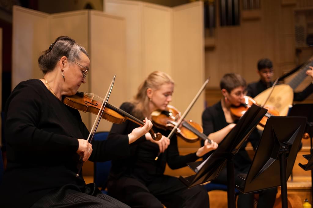 A strings teacher and students in rehearsal