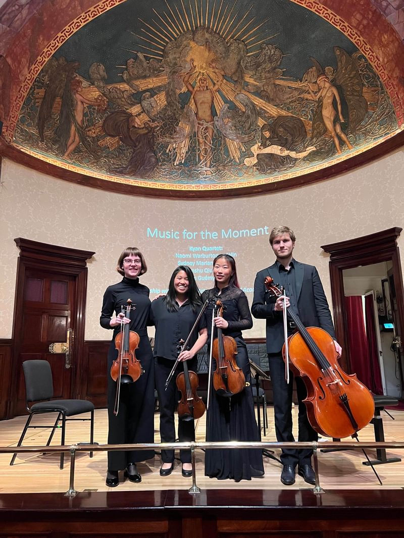 A string quartet pose for camera on stage