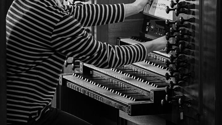 Close up of an organ student adjusting the drawknobs in an organ (black and white)