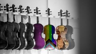 Violins hanging from a rack, edited to include the LGBT flag on the back of one of the bodies