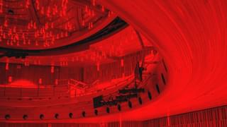 Decorative red image of the ceiling of a theatre with ornate light fixtures