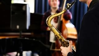 A saxophone player from over the player's shoulder