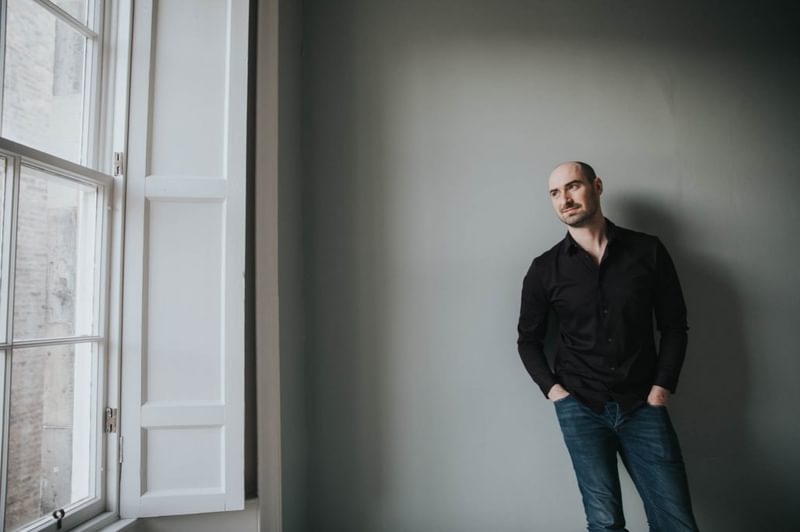 Peter Whelan standing next to a window on a bleak day