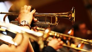 Close up of a row of players holding trumpets with the faces out of shot
