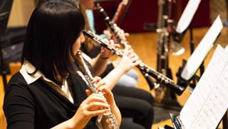 A row of woodwind players seen from the side