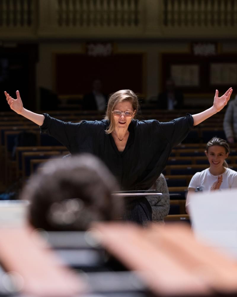 A conductor raises both arms
