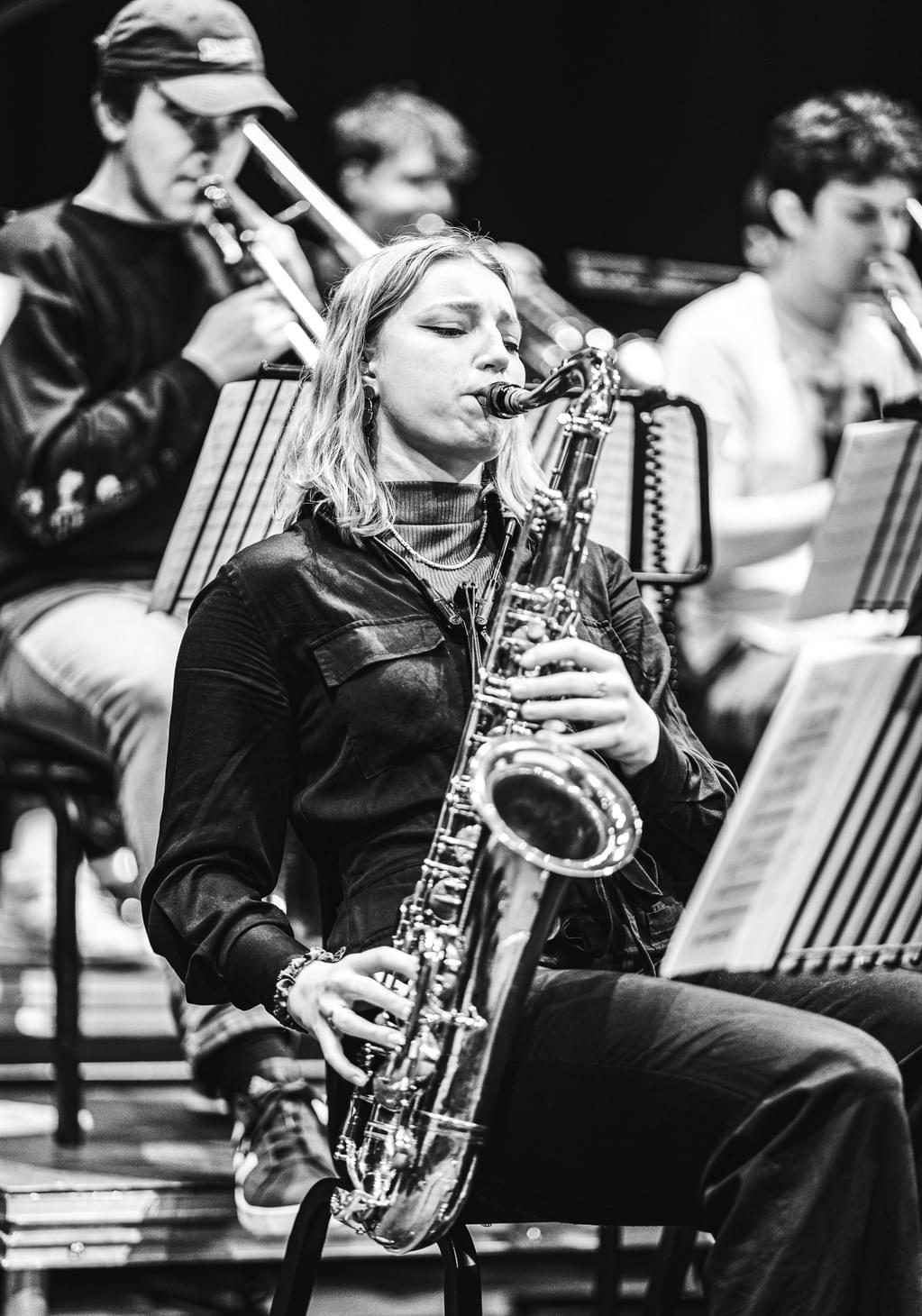 A jazz student performs within a busy ensemble (black and white)