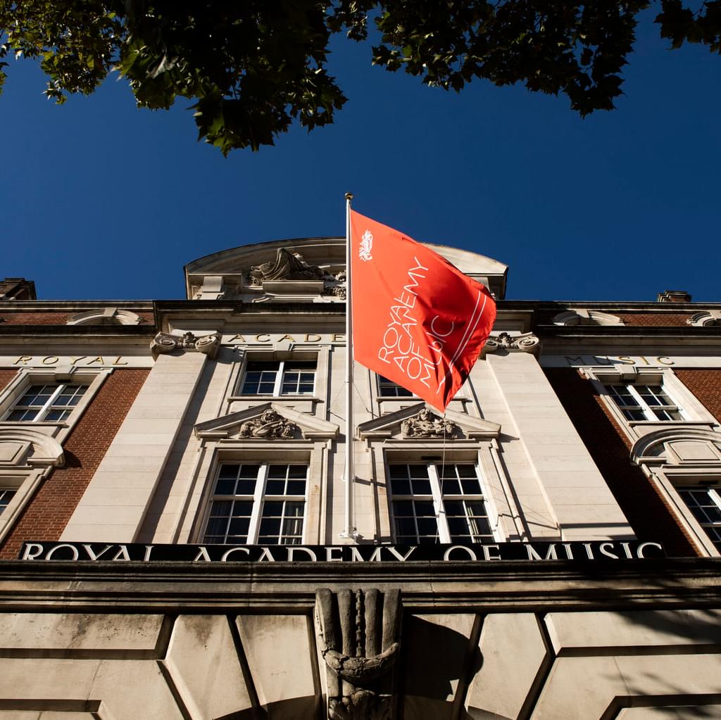 Perspective of The Royal Academy of Music's Flag flying outside the front of the building on a sunny day, from directly below