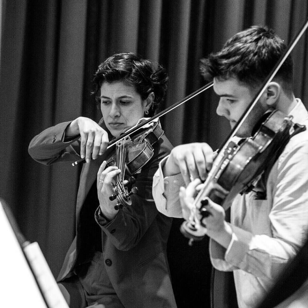A violin duo read and play sheet music side by side