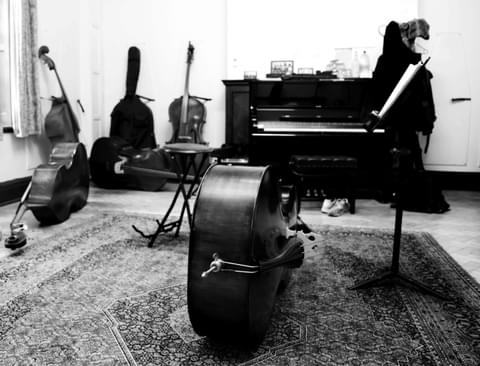 A cello sits on its side in an empty rehearsal room