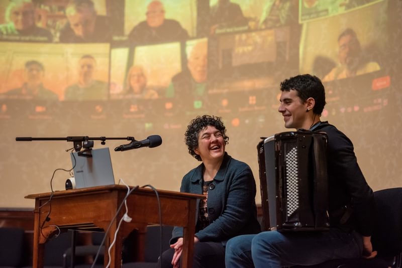 An accordion player and interviewer on stage