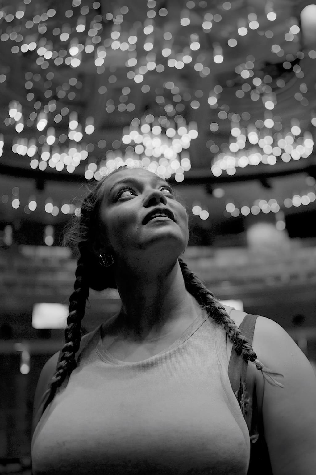 A student peers up at a ceiling dotted with many ornate lights