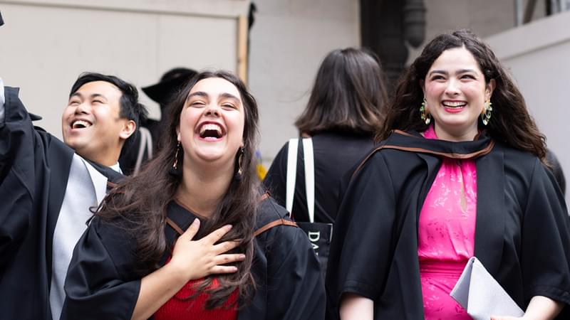 Students in graduation robes laugh together