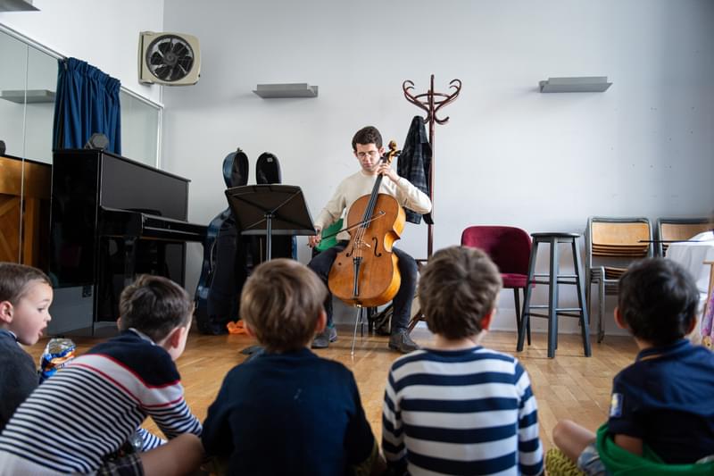 A cellist performs to a small workshop group