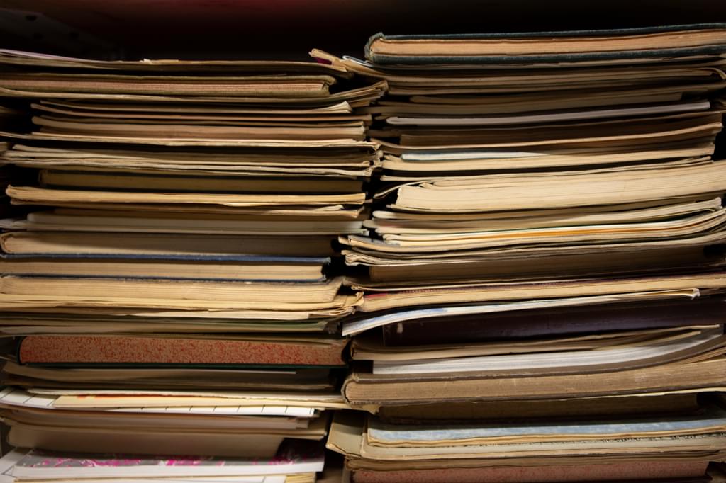 A side-on view of a shelf stacked with many musical manuscripts