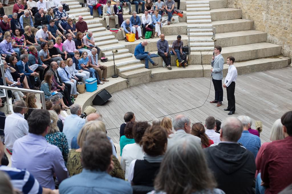 Two speakers in front of an audience sat in an amphitheatre
