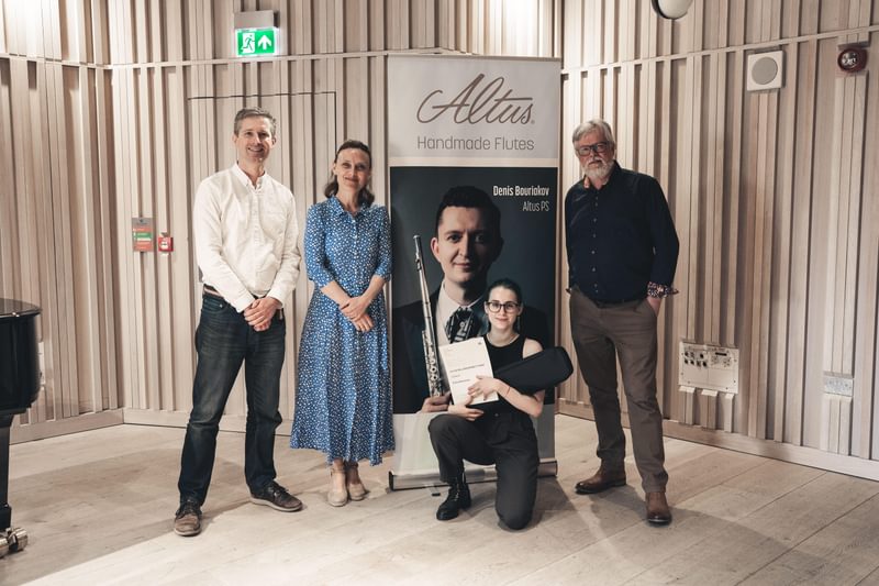 A group of people pose for camera next to a pop up banner for Altus Flutes
